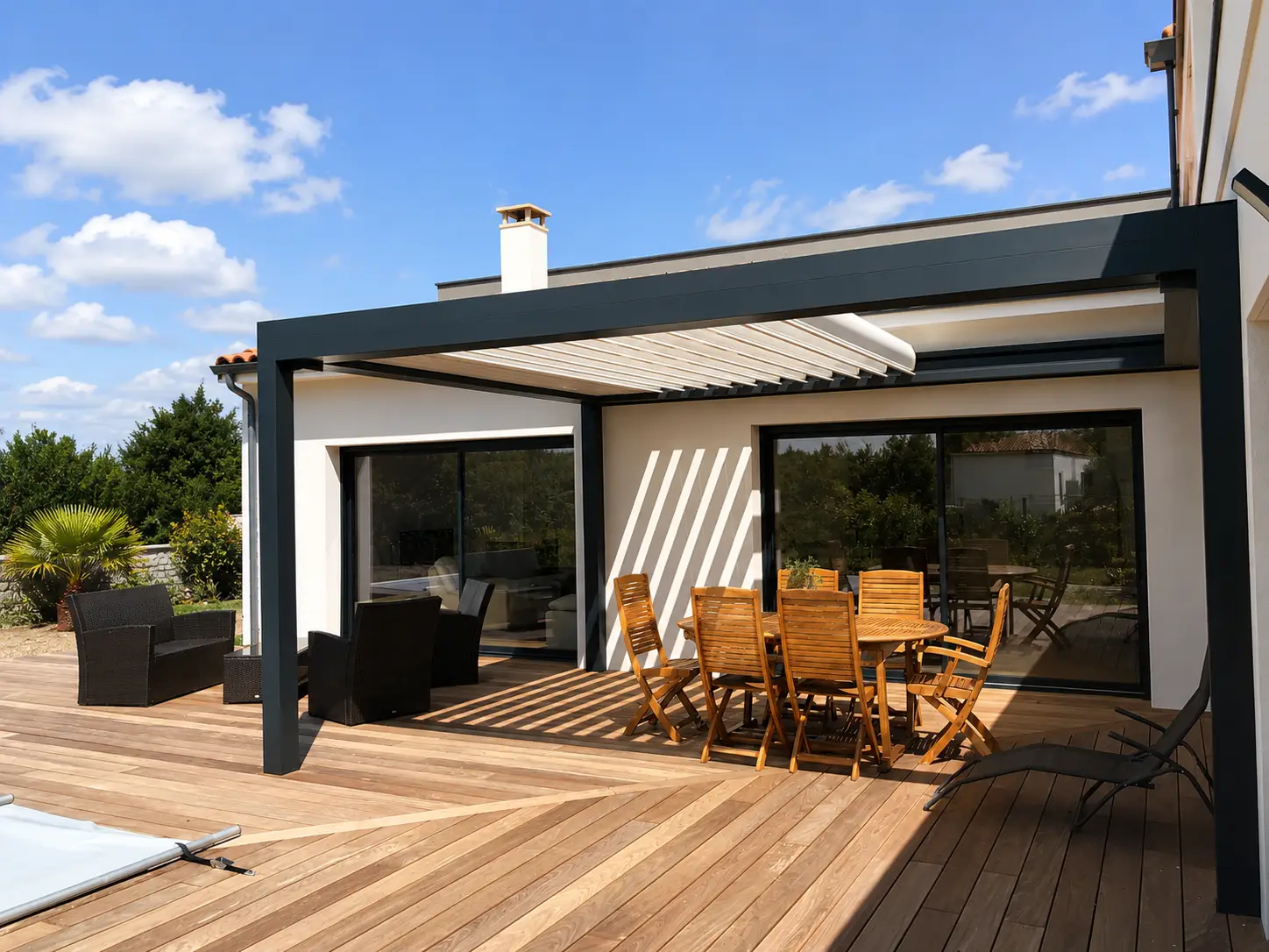 Pergola bioclimatique adossée à une maison, au-dessus d'une terrasse en bois